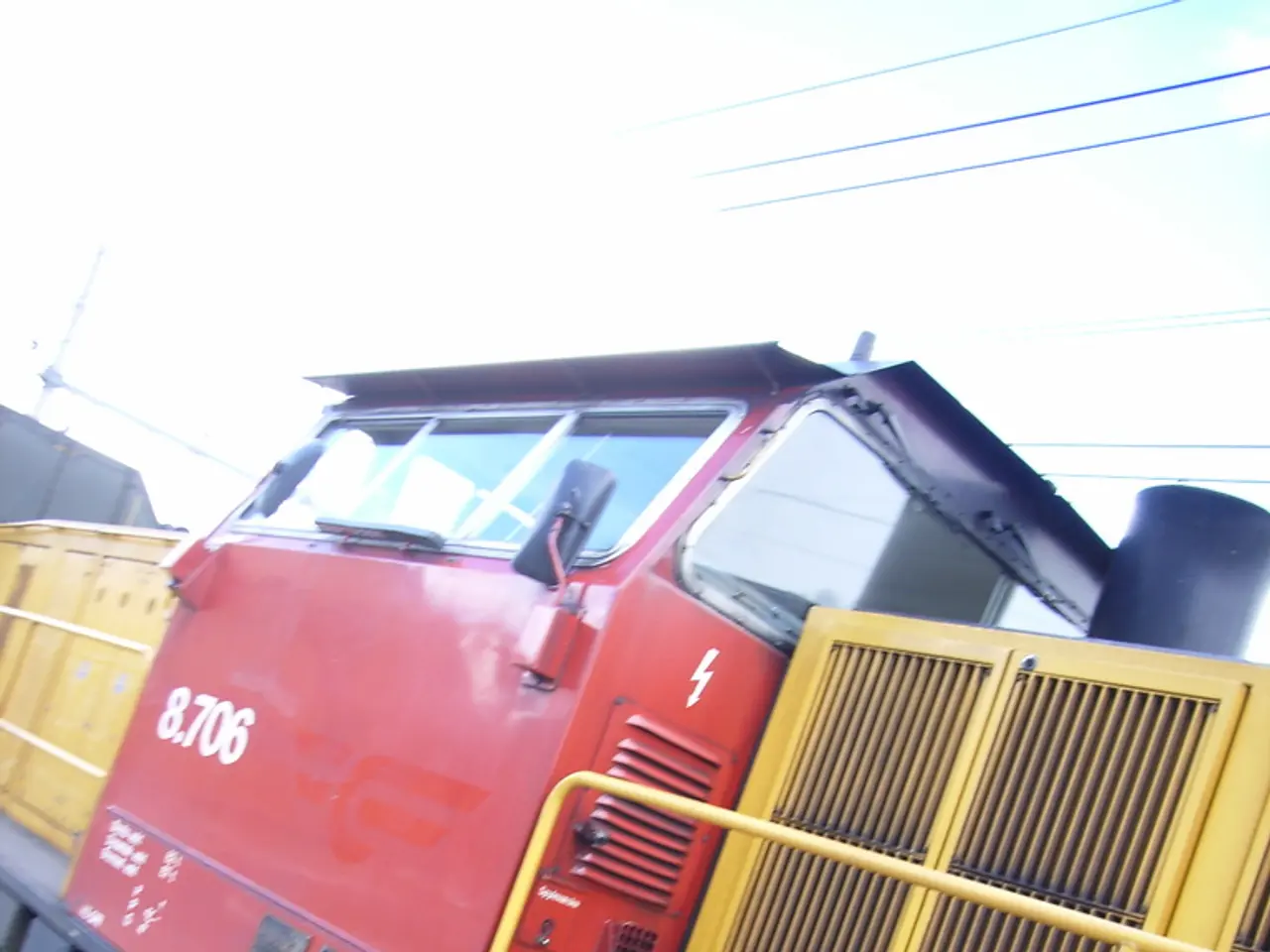 In this image there is a train on the track. In the background there are a few cables and the sky.