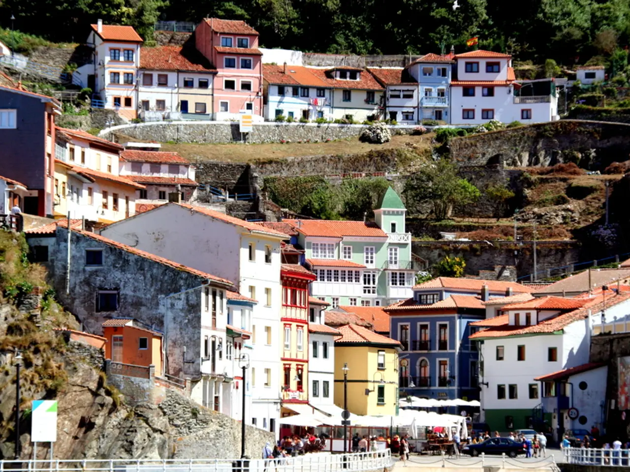 In this image there is a fence where people are standing and also there are buildings covered on...