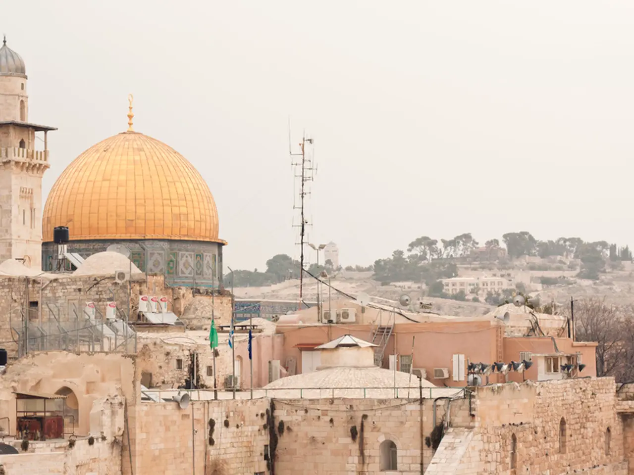 There are many buildings with brick wall. Also there are dish antennas. In the back there are trees...