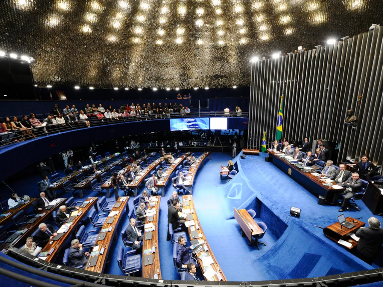 In the image it looks like some conference, there is a stage and on the stage there are a group of...