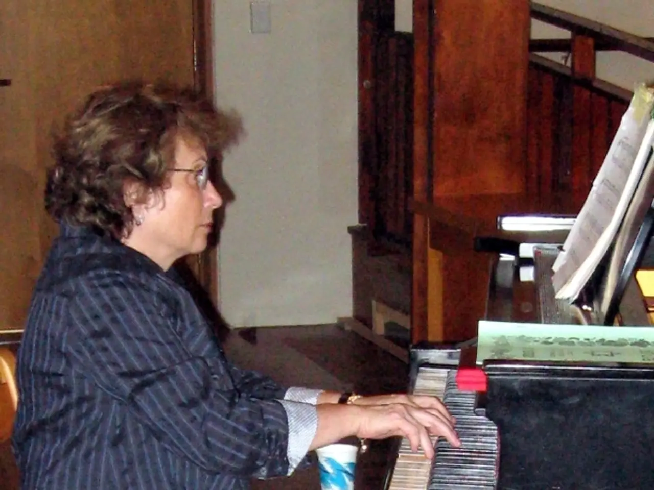 A woman is sitting on the chair and playing the musical instrument.