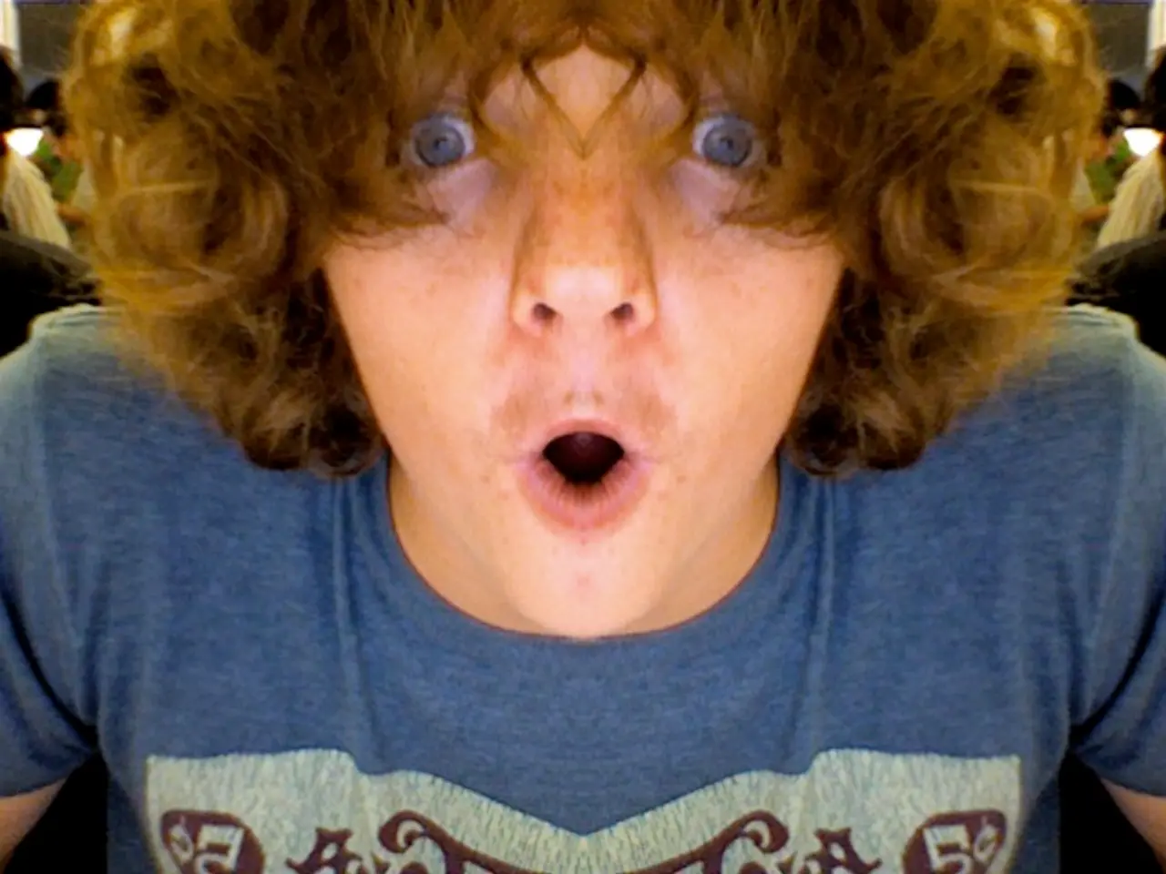 In this image we can see a man. He is wearing a blue color T-shirt and looks like he is shouting.