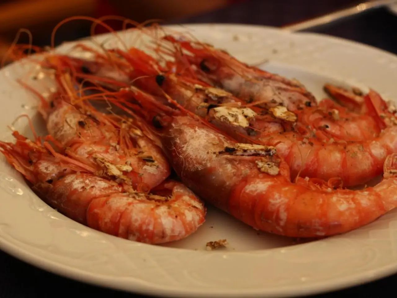 In this image we can see some seafood on the plate. There are few objects at the right top most of...
