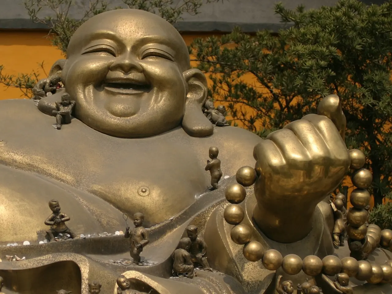 It is a laughing Buddha statue which is in gold color. In the right side there are trees and this...