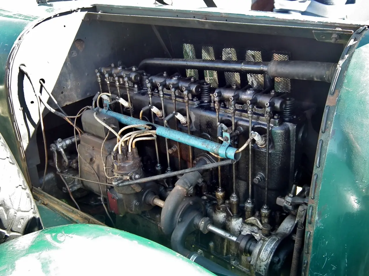 In the middle of this image, there is an engine of a vehicle. On the left side, there is a wheel of...