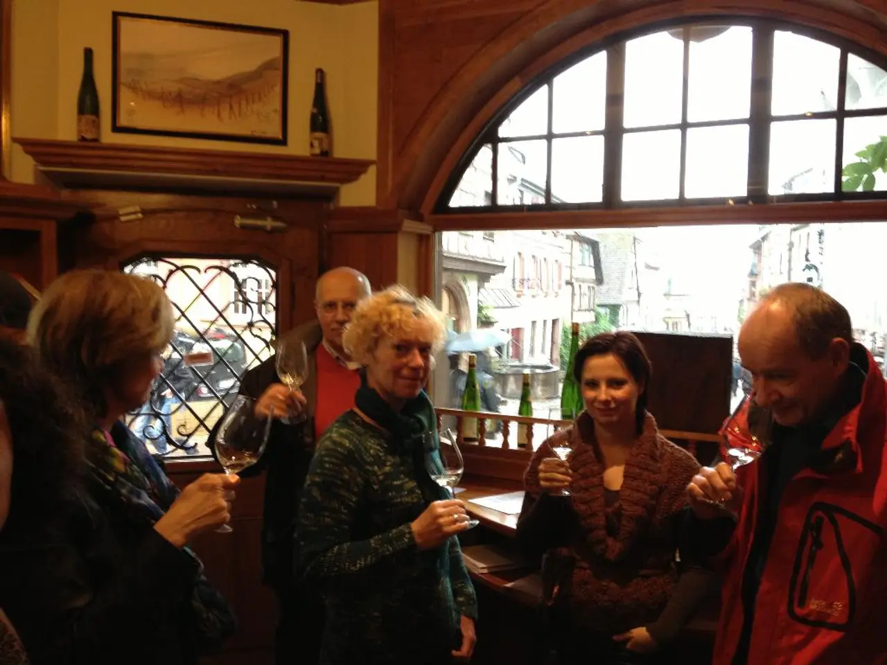 In this picture we see 5 people who are holding alcohol glasses and in the background we have...