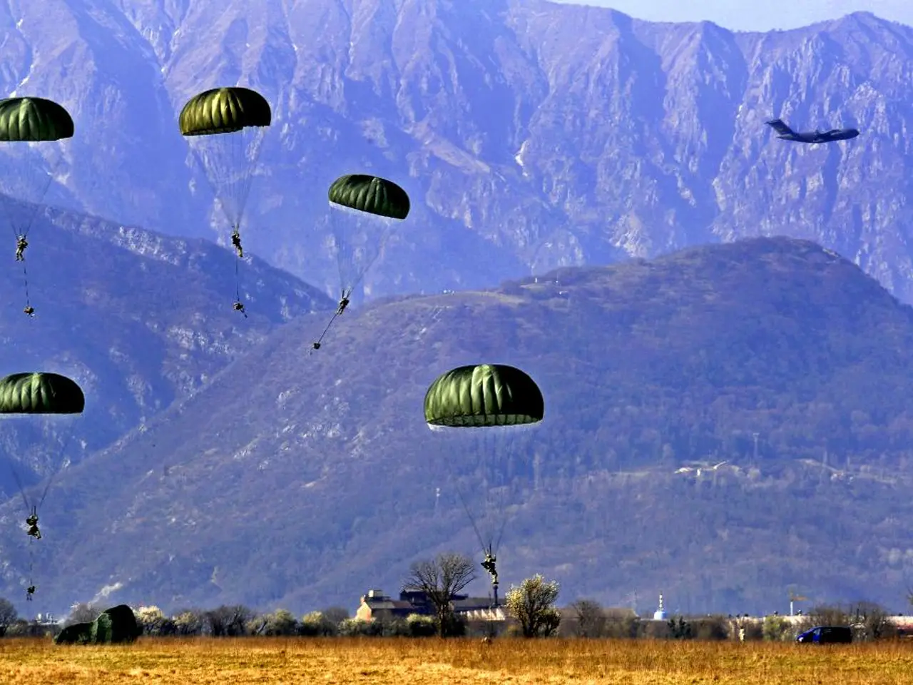 In this picture we can see the people with the paratroopers and an airplane in the air. Under the...