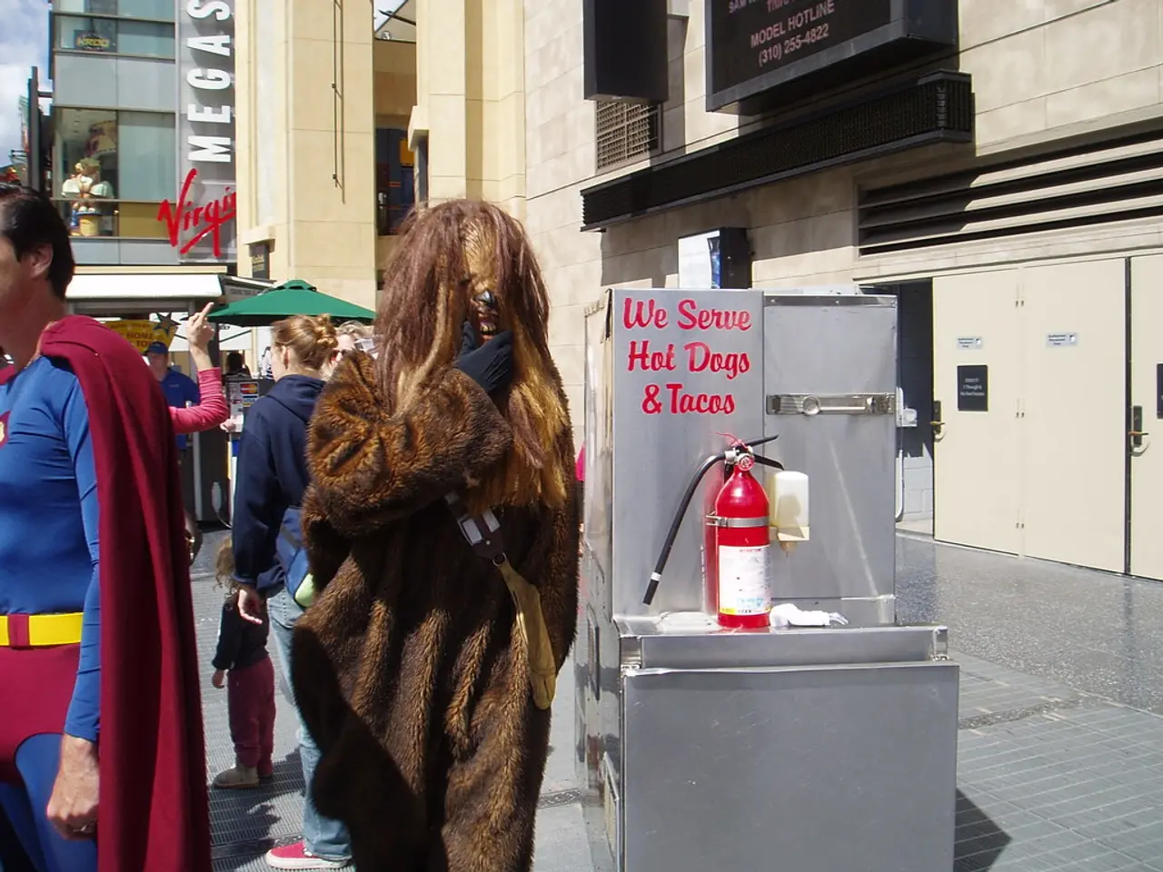 There are many people. Some are wearing costumes. There is a box with something written on that....