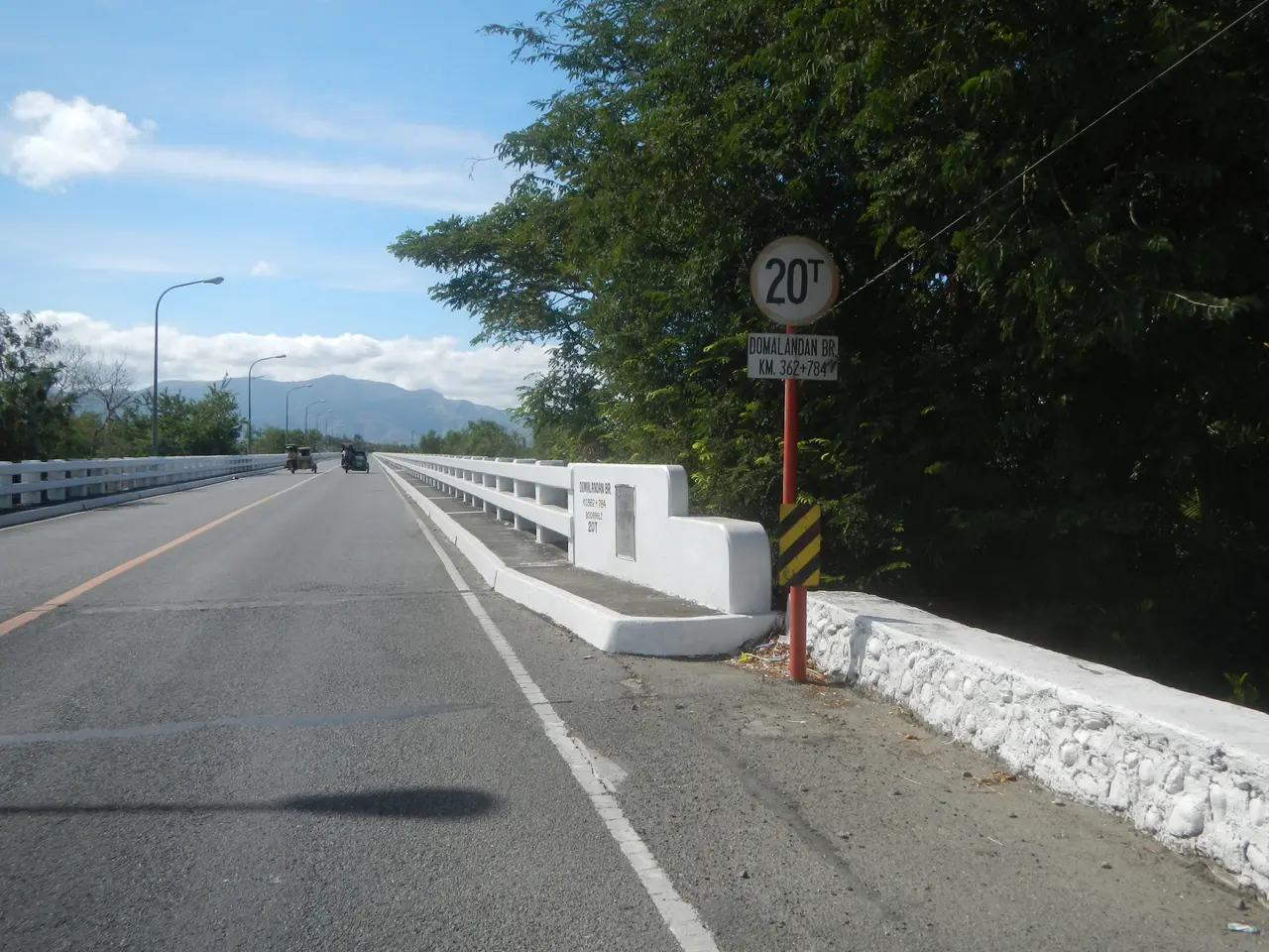 The image shows a carriageway with vehicles driving on it, a speed limit sign on the side of the...