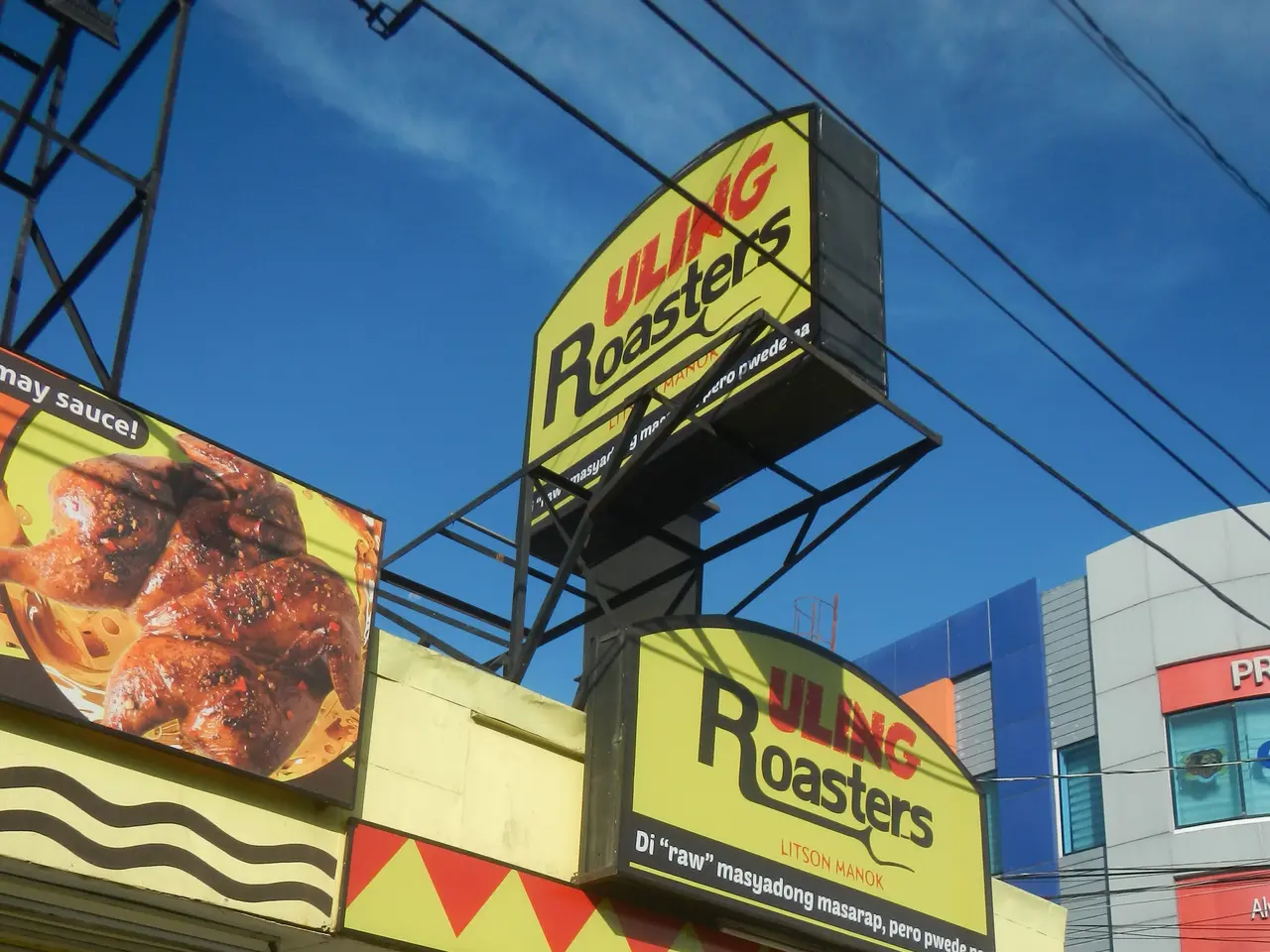 The image shows a restaurant with a sign that reads "Uling Roasters" on the side of it, surrounded...