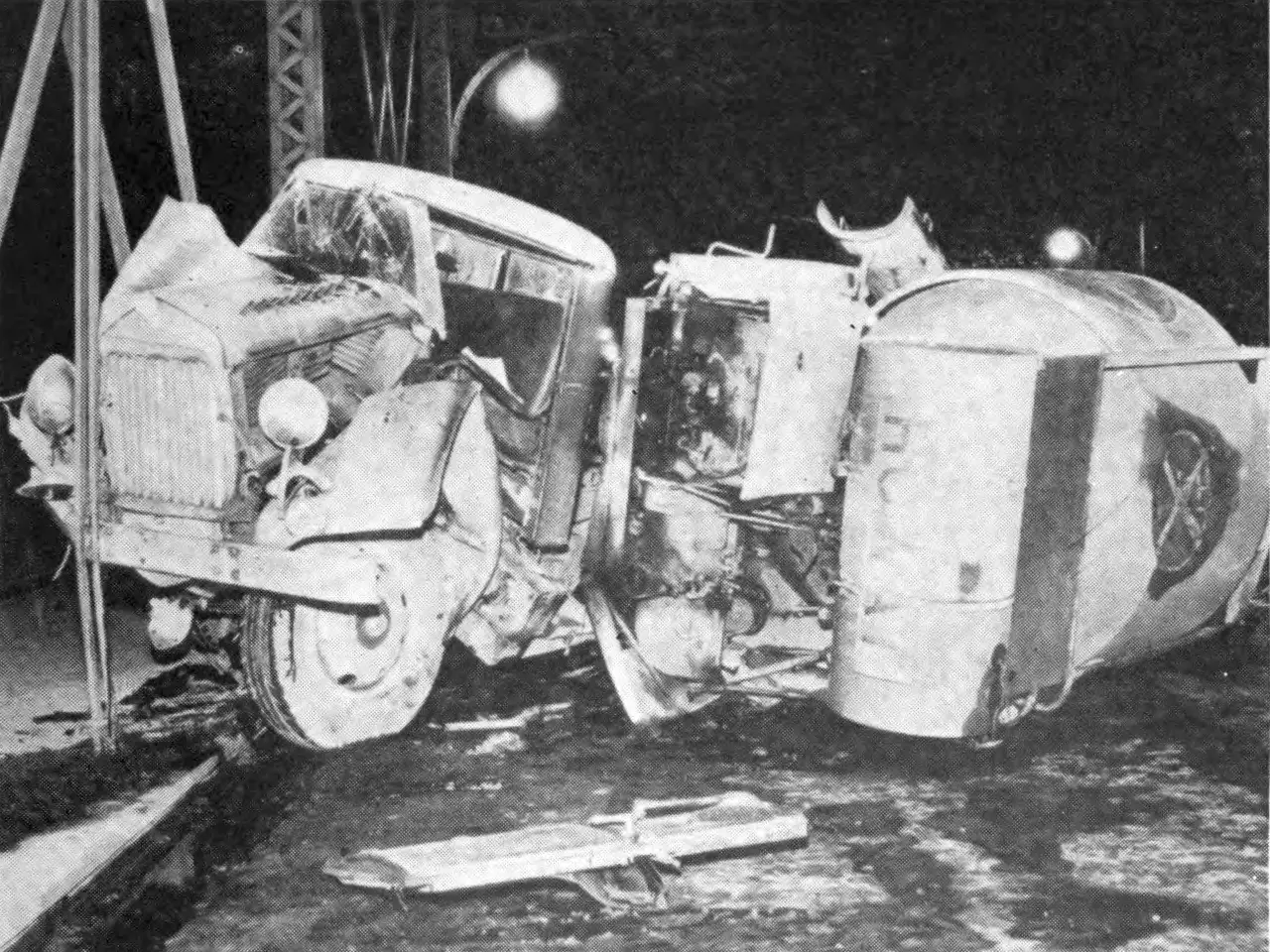 The image shows a black and white photo of a car that has been flipped over on the side of the...