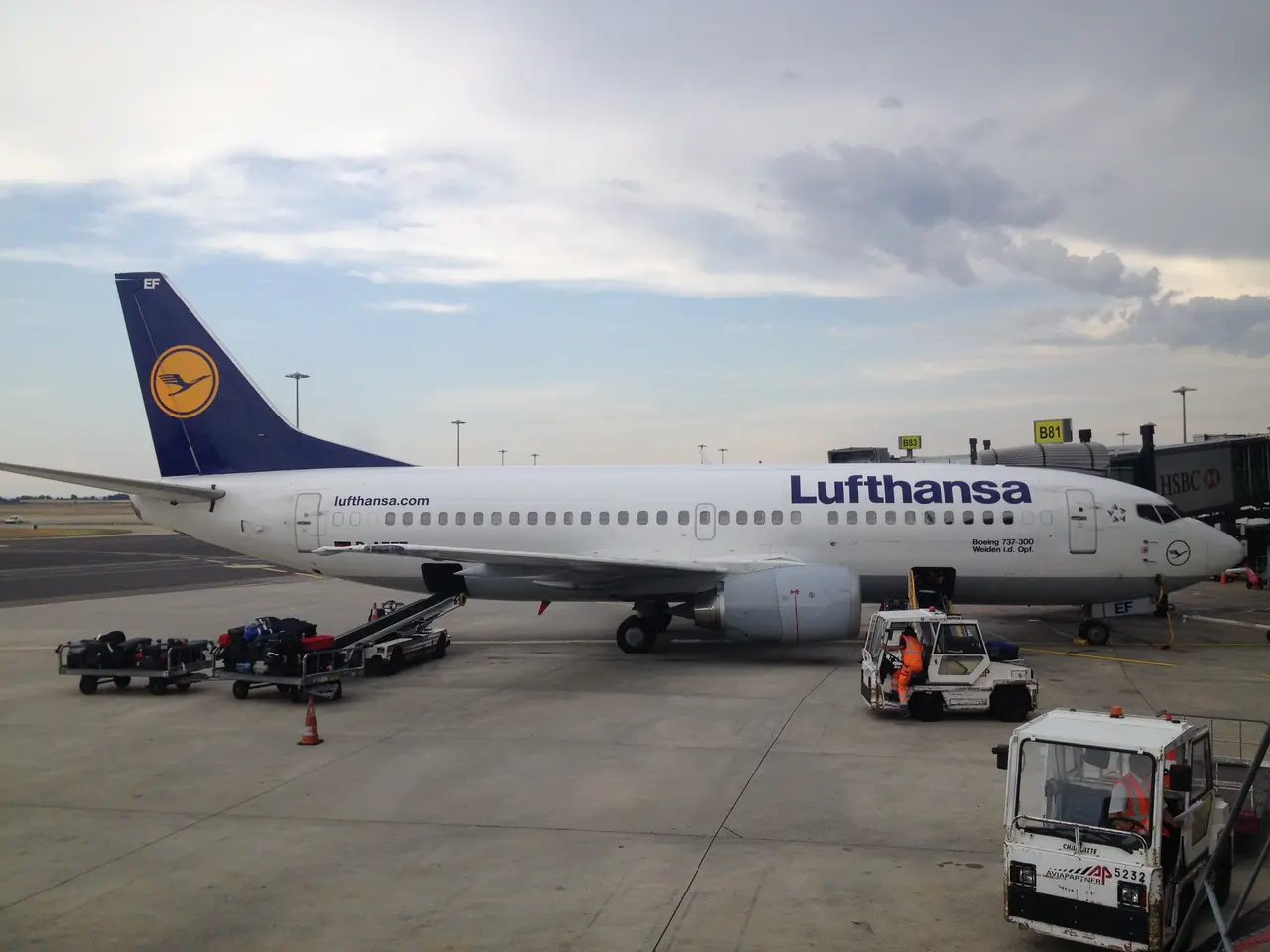 The image shows a Lufthansa Airbus A320-200 at Frankfurt Airport, with vehicles and trolleys on the...
