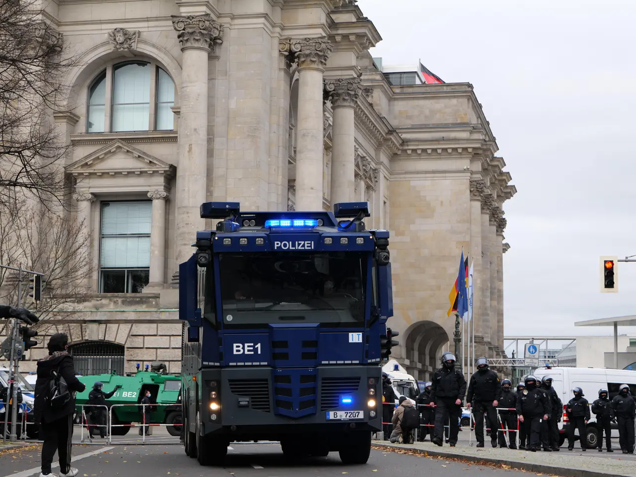 The image shows a group of police officers standing in front of a large building with windows,...