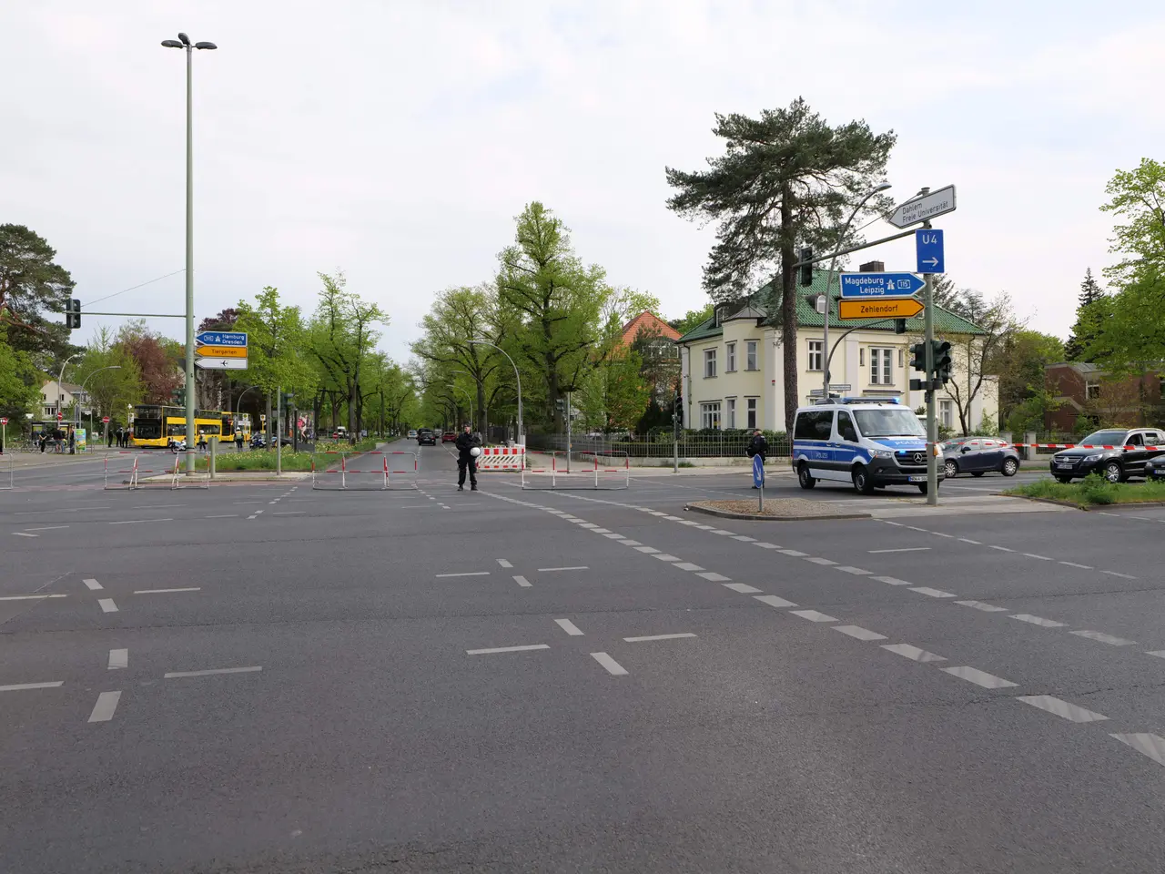 The image shows a roundabout with a police car parked on the side of the road. There are vehicles...