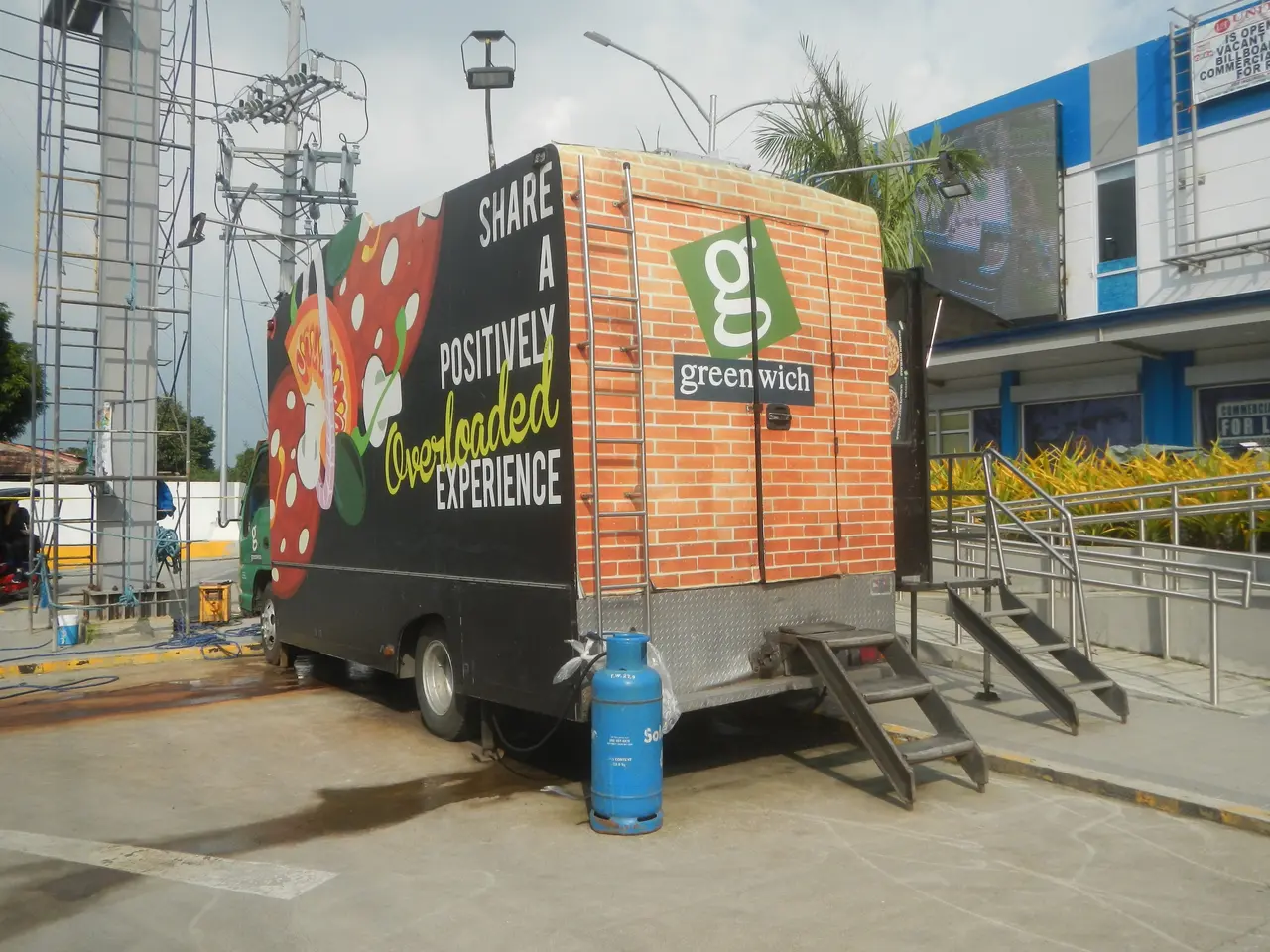 The image shows a truck parked in front of a building with a sign that reads "Share a Positively...