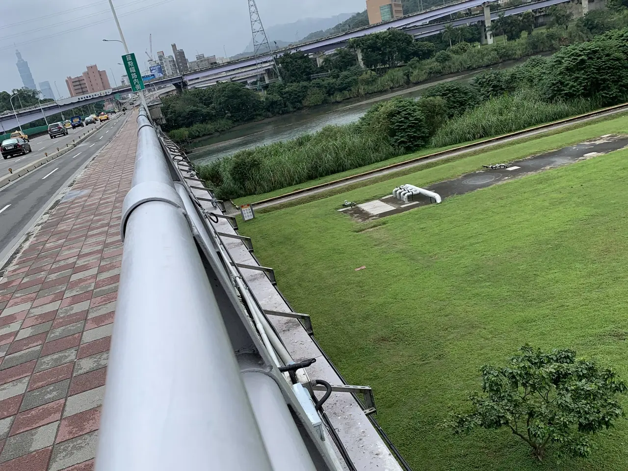 The image shows a view of a city from the top of a building, with vehicles on the road below,...