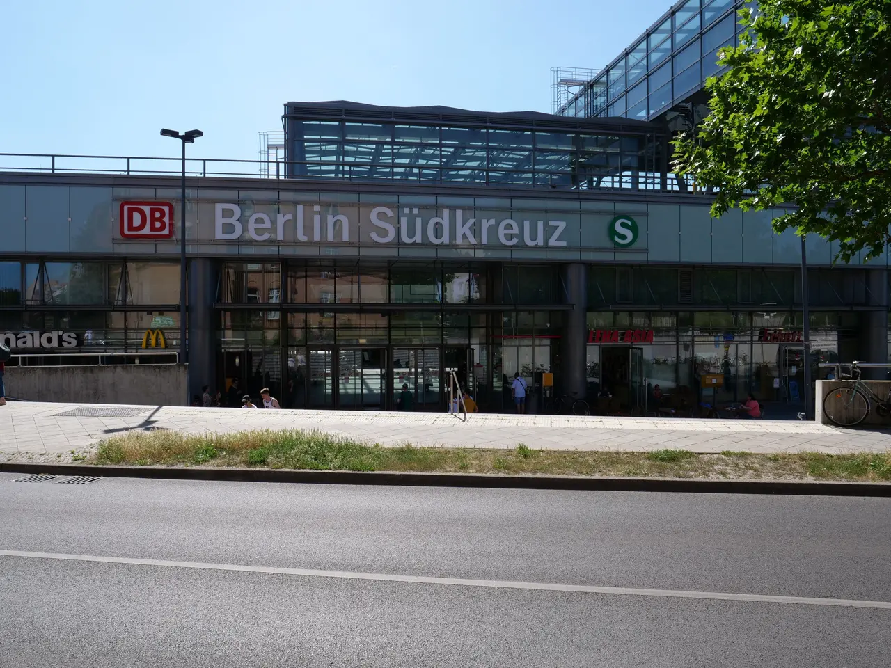 The image shows the Berlin Sudkreuz train station in Berlin, Germany. It is a large building with...