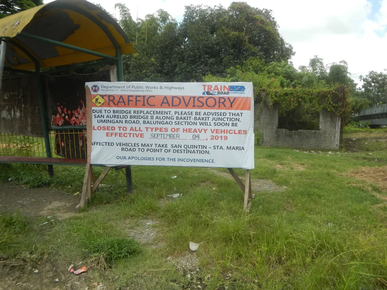 The image shows a bus stop with a sign that reads "Traffic Advisory" in front of it, surrounded by...