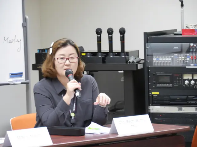 In the image we can see a woman wearing clothes, identity card and spectacles, she is holding a...