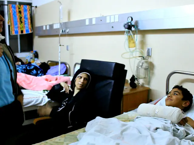 In the picture we can see inside view of the hospital with beds and patients on it and between the...