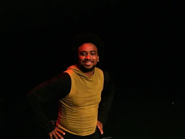 In the middle of this image, there is a person in a T-shirt, smiling and doing a performance on a...