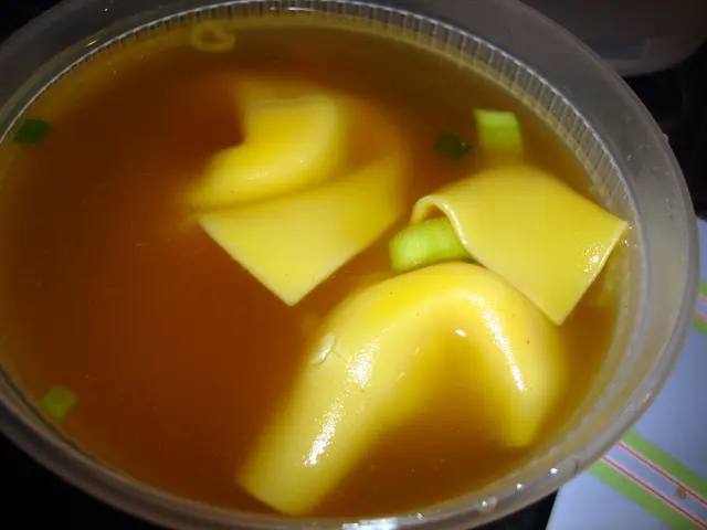 There is a soup in the bowl which has some yellow color objects in it.