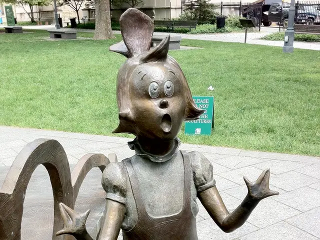 In this image there is a metal structure of a girl, behind the structure, there is grass, behind...