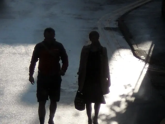 In this picture there is a man and a woman in the center of the image on a road.