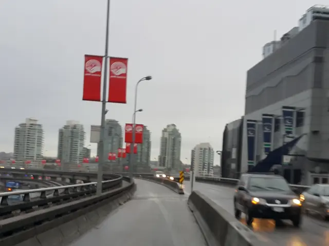 There are few vehicles on the road and there are buildings in the background and there are few...