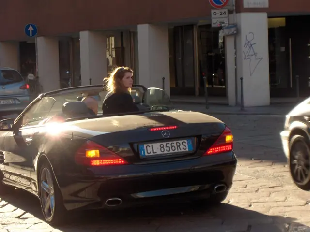 There is a woman inside the car. These are the lights and this is road. There is a building and...