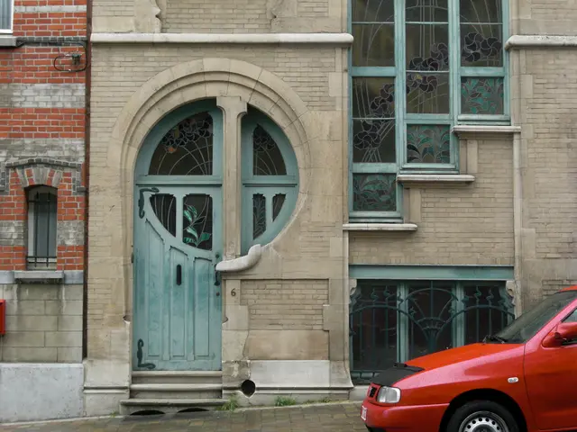 In the picture there is a car and behind the car there are two buildings.