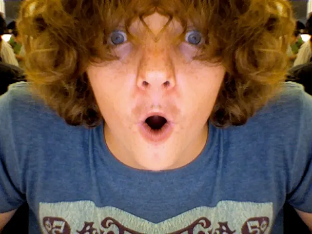 In this image we can see a man. He is wearing a blue color T-shirt and looks like he is shouting.