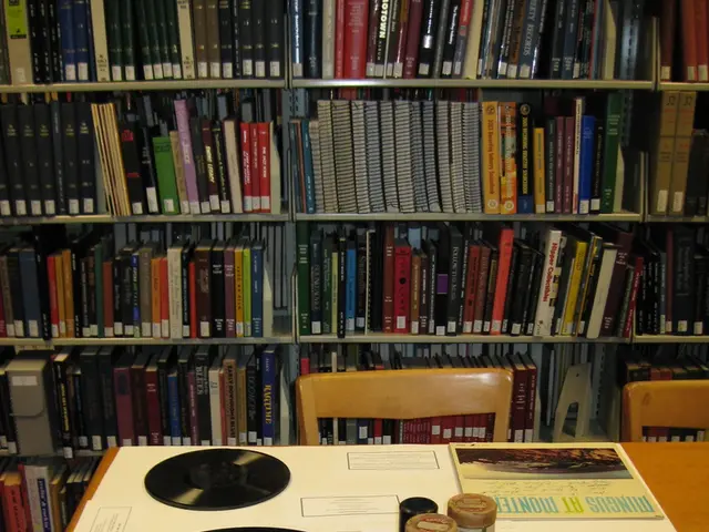 In this image I can see few Cd's and few objects on the table. Back I can see chairs and book-rack....