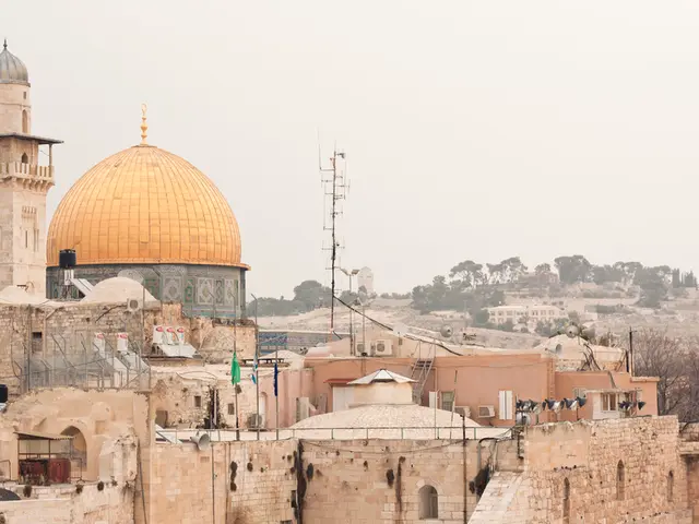 There are many buildings with brick wall. Also there are dish antennas. In the back there are trees...
