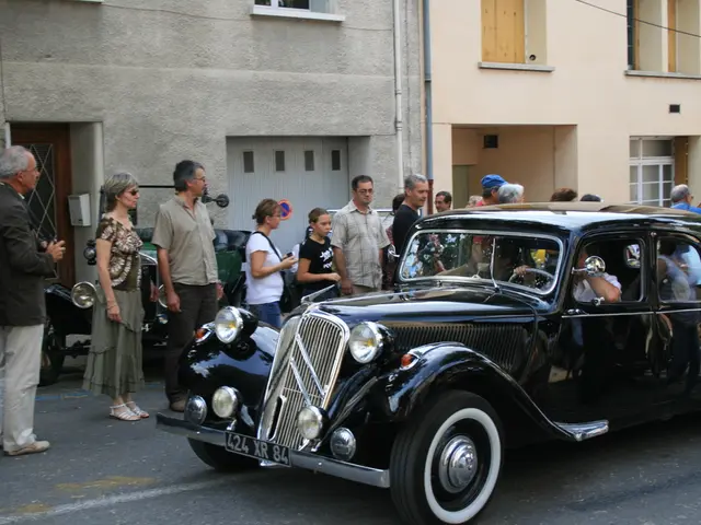 It's a car on the road. In the left side there are people standing behind them there are buildings.