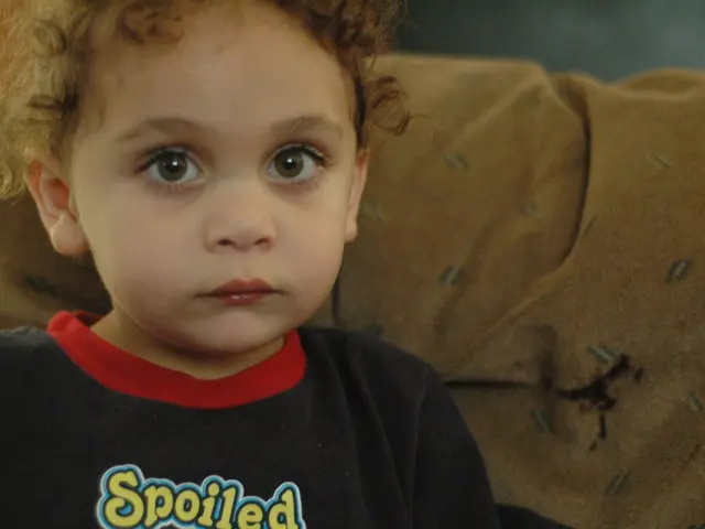 As we can see in the image there is a kid who is having curly hair and wearing a black shirt on...