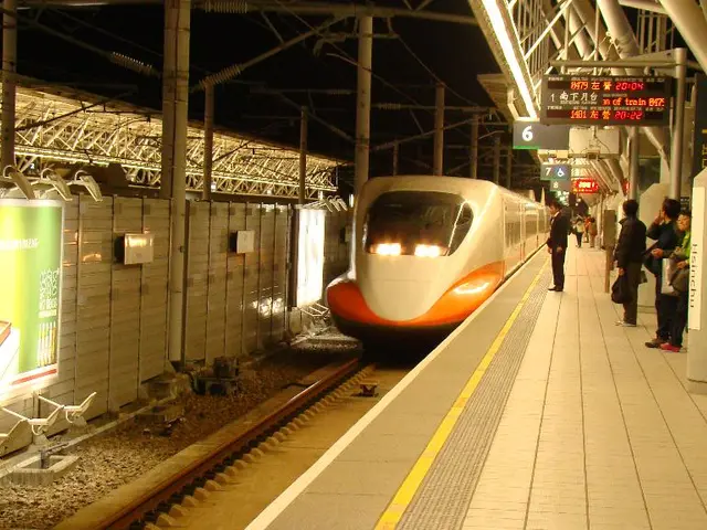 In this image there are few persons standing on the platform. A train is on the rail track. Left...