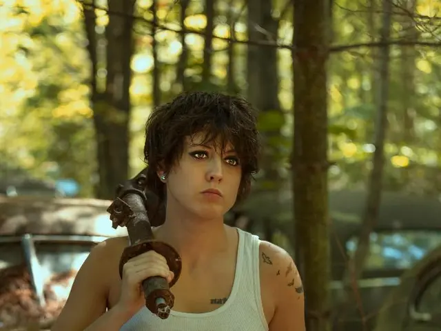 This is the woman holding an iron object and standing. In the background, I can see the cars. These...