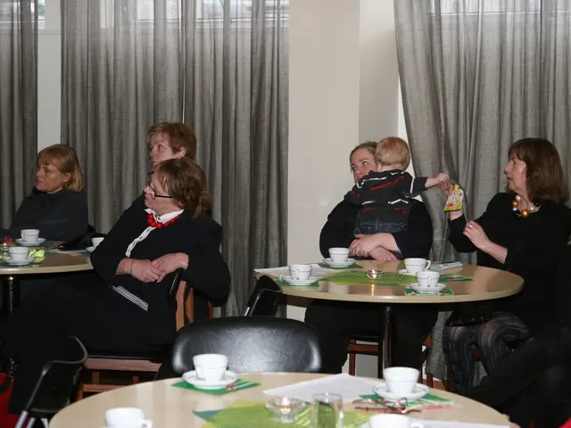 This image is taken in a restaurant there are many people sitting on the chairs. On the right there...