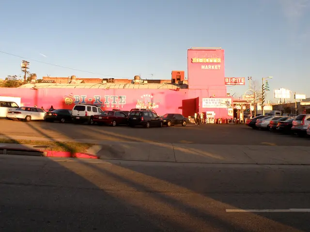 In this image there is a building in the middle. In front of the building there are so many cars...