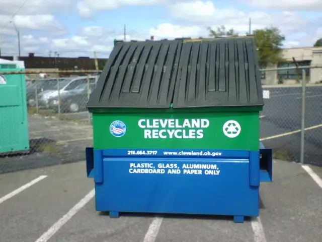 In this image there is a waste container on the ground. There are logos and text on the waste...