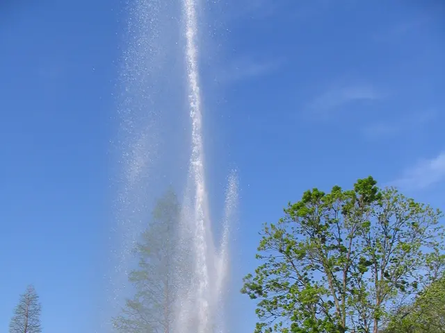In this image there is a water fountain in the middle. In the background there is a house on the...