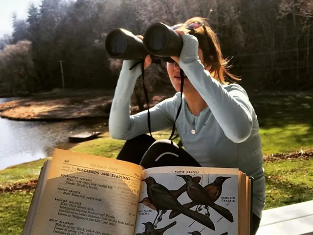 In the image there is a woman sitting on a bench and beside her there is a book with some pictures...