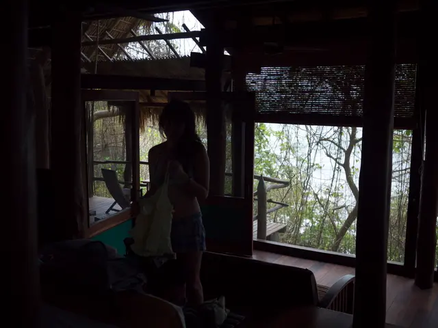 This image is taken indoors. In the middle of the image a girl is standing and she is holding a bag...