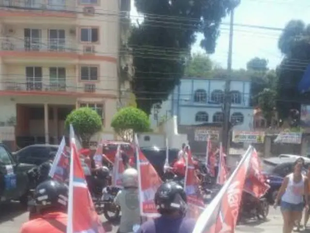 In this image there are group of persons riding a bikes by holding a flag and the back ground there...