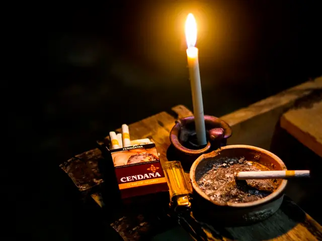 In the image we can see a candle, cigarettes, box, lighter and a container.