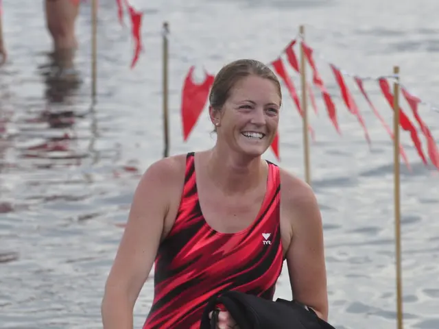 In the image there is a woman in the foreground, she is wearing a swimsuit and smiling. Behind the...