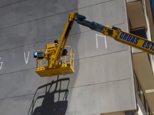 In the image we can see there are paint buckets kept on the ground and there is a building. There...