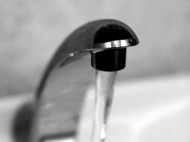 This is a black and white image, in this image there is a tap and water flowing from the tap.