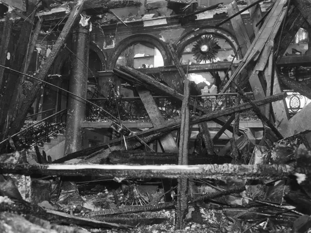 The image shows a black and white photo of the interior of a building that has been destroyed by a...